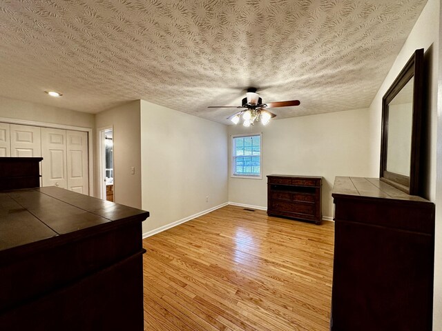 unfurnished living room with a textured ceiling, light hardwood / wood-style floors, and ceiling fan