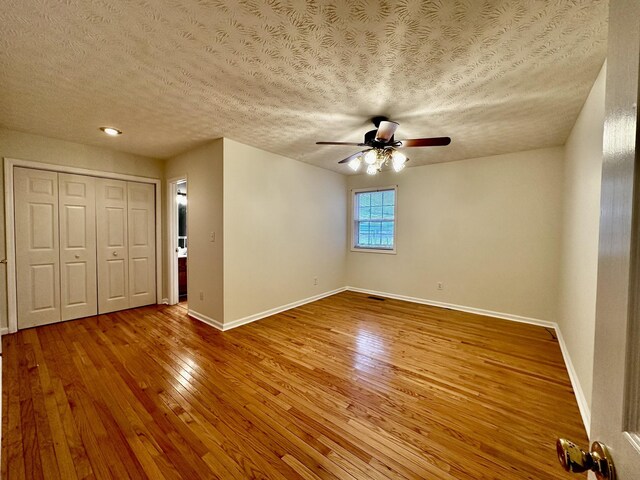 interior space featuring ceiling fan, a textured ceiling, baseboards, and wood finished floors