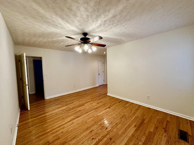 unfurnished room featuring a ceiling fan, baseboards, visible vents, and light wood finished floors