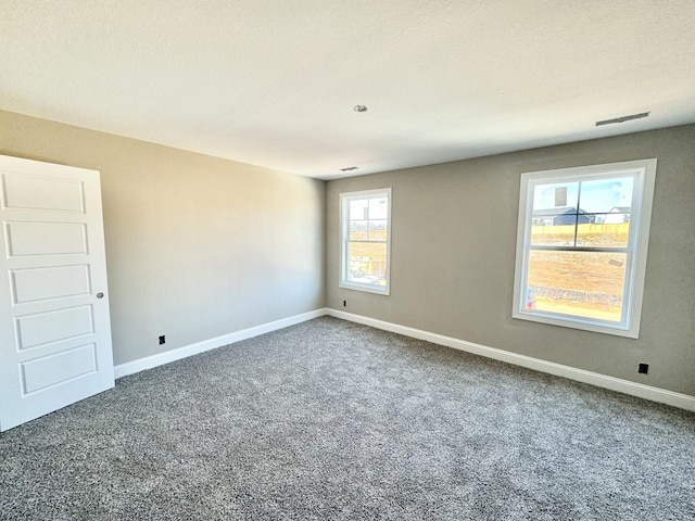 carpeted empty room featuring visible vents and baseboards