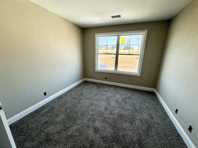 spare room featuring baseboards and dark colored carpet