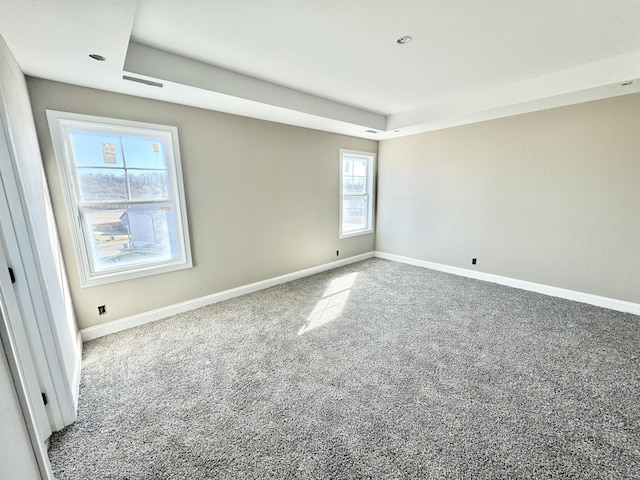 empty room with a tray ceiling, baseboards, and carpet floors