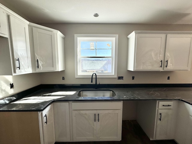 kitchen featuring sink, white cabinets, and dark stone counters