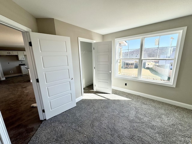 unfurnished bedroom with dark carpet and a closet