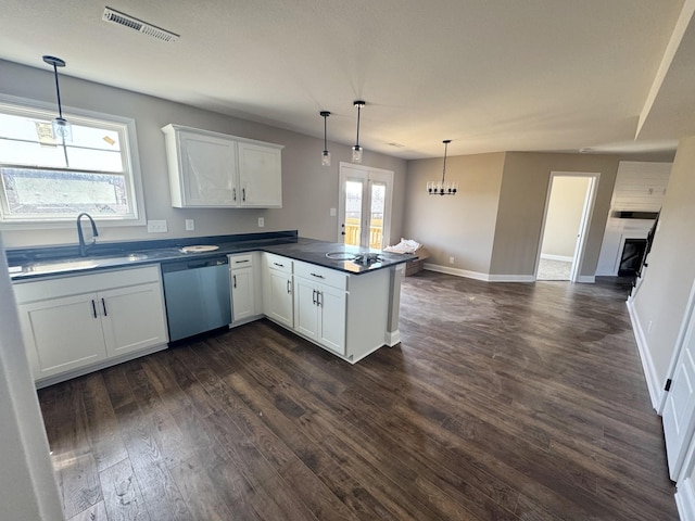 kitchen with visible vents, a peninsula, a sink, stainless steel dishwasher, and dark countertops