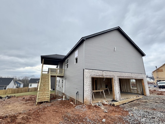 view of property exterior featuring stairs, fence, a patio area, and brick siding