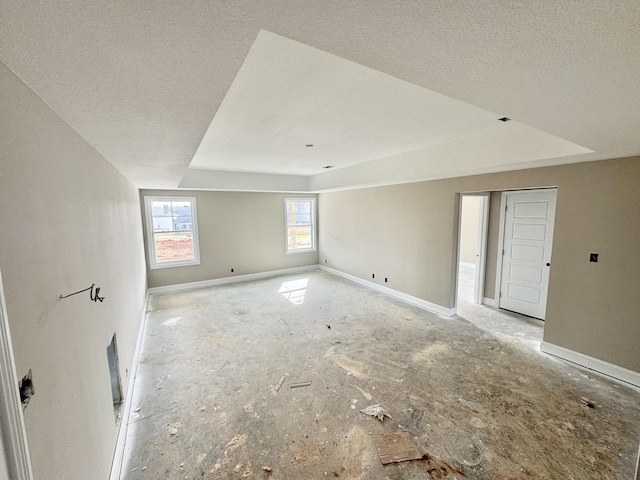 unfurnished room featuring a raised ceiling, baseboards, and a textured ceiling