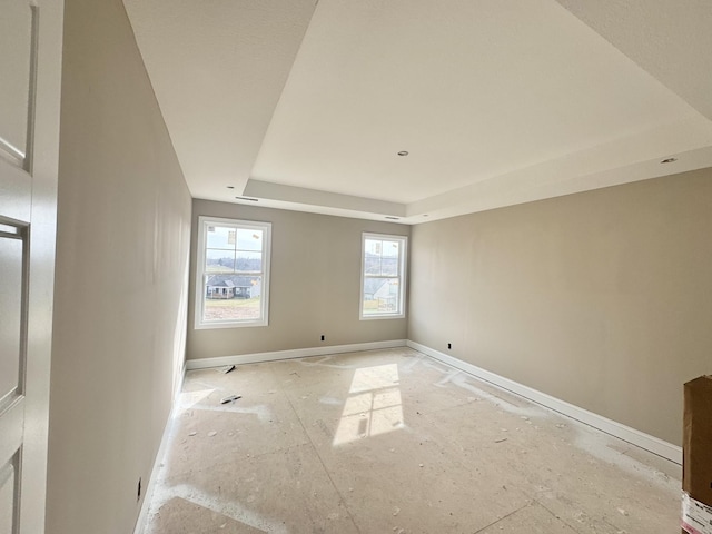 spare room featuring a raised ceiling and baseboards