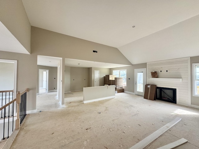 unfurnished living room featuring high vaulted ceiling, a large fireplace, and baseboards