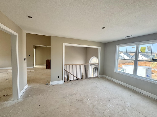 spare room featuring visible vents, baseboards, and a textured ceiling