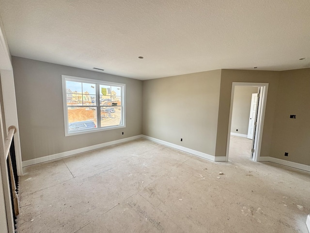 unfurnished room with baseboards and a textured ceiling