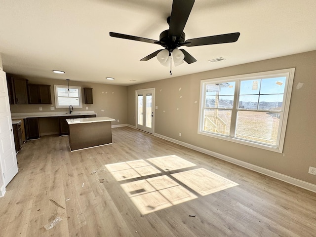 kitchen with a center island, sink, light wood-type flooring, and decorative light fixtures