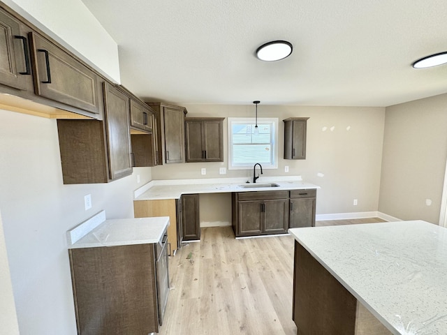 kitchen featuring dark brown cabinetry, sink, pendant lighting, and light hardwood / wood-style floors