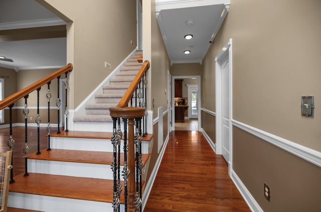 stairway with ornamental molding and wood-type flooring