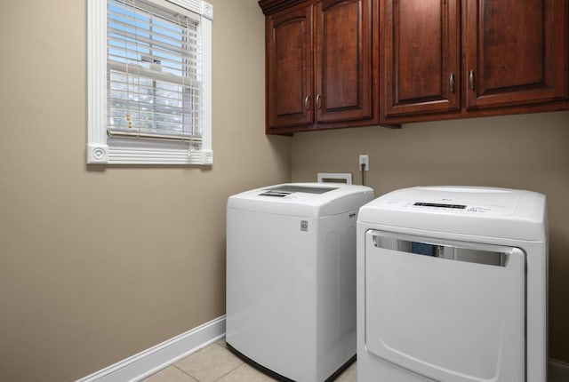 laundry area with light tile patterned floors, separate washer and dryer, and cabinets