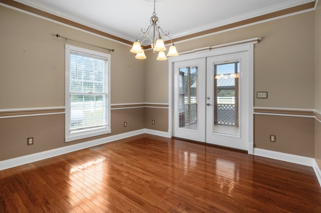 unfurnished dining area with ornamental molding, french doors, hardwood / wood-style flooring, and a chandelier