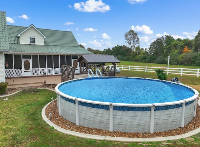 view of swimming pool featuring a lawn and a sunroom