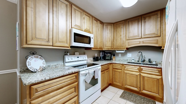 kitchen with light stone countertops, sink, light tile patterned floors, and white appliances