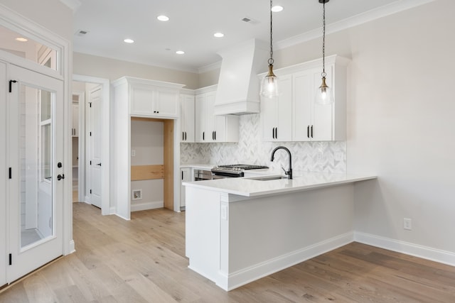 kitchen with sink, white cabinetry, decorative light fixtures, and custom exhaust hood