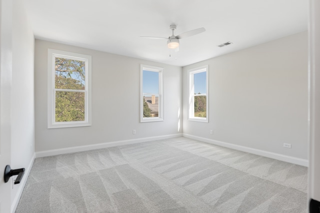 spare room with ceiling fan, a healthy amount of sunlight, and light colored carpet