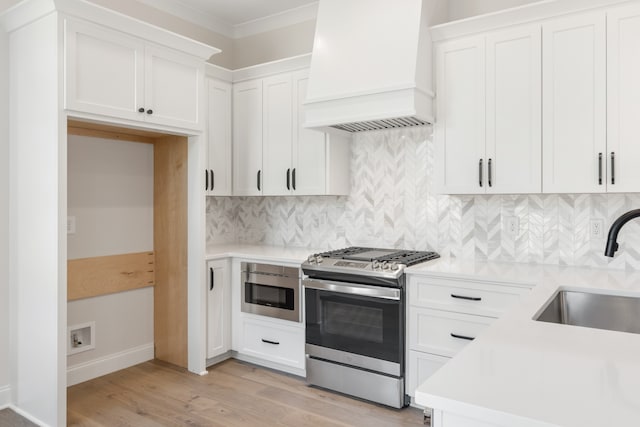 kitchen with white cabinetry, light hardwood / wood-style flooring, custom range hood, sink, and stainless steel appliances