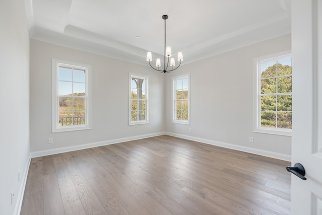 empty room with a notable chandelier, light wood-type flooring, and crown molding