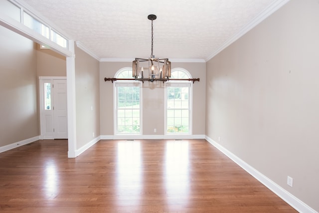 unfurnished dining area featuring hardwood / wood-style flooring, ornamental molding, and a textured ceiling