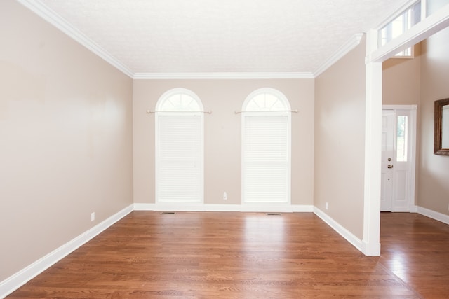 empty room with ornamental molding, dark hardwood / wood-style floors, and a textured ceiling