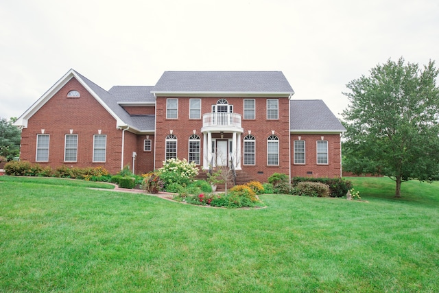 colonial house featuring a front lawn and a balcony