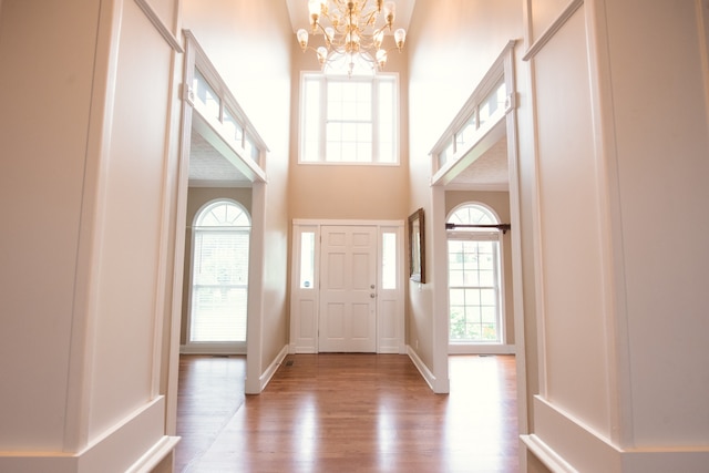 entrance foyer with a high ceiling, wood-type flooring, and a chandelier