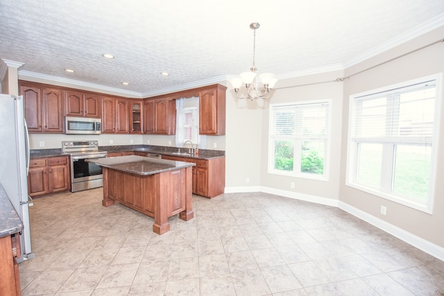 kitchen featuring crown molding, a center island, pendant lighting, an inviting chandelier, and appliances with stainless steel finishes