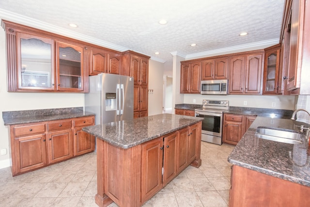 kitchen with a kitchen island, appliances with stainless steel finishes, a textured ceiling, crown molding, and sink