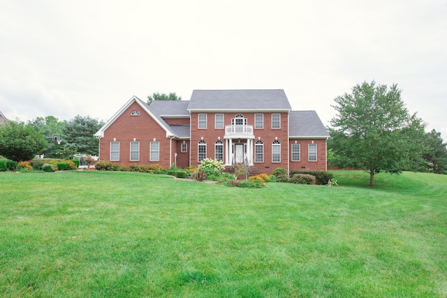 colonial inspired home featuring a front lawn and a balcony