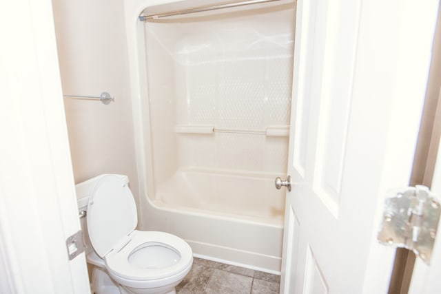 bathroom with toilet, shower / washtub combination, and tile patterned flooring