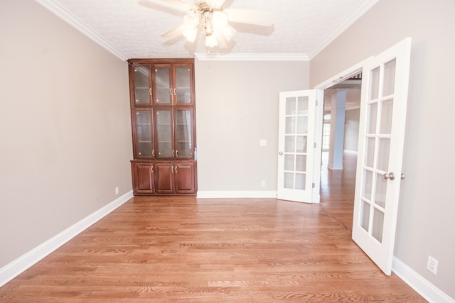 unfurnished room featuring french doors, crown molding, light wood-type flooring, and ceiling fan