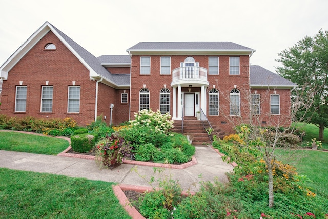 colonial inspired home with a front yard and a balcony