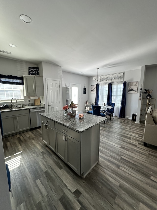 kitchen with dark hardwood / wood-style floors, hanging light fixtures, a center island, gray cabinets, and stainless steel dishwasher