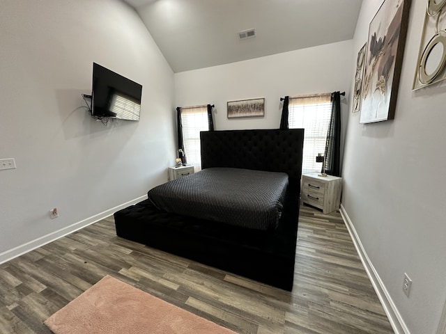 bedroom with dark wood-type flooring and lofted ceiling