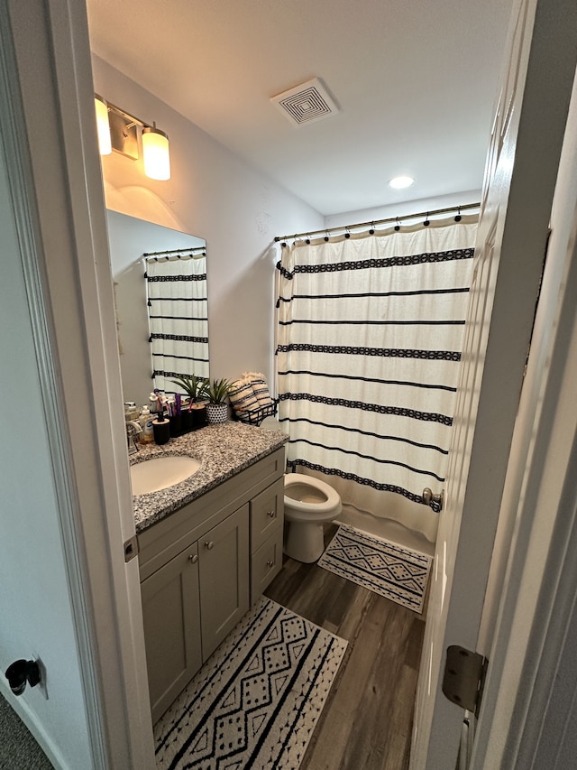 full bathroom featuring vanity, shower / bath combination with curtain, hardwood / wood-style flooring, and toilet