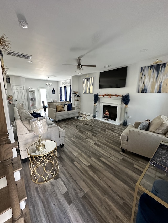 living room featuring dark hardwood / wood-style flooring and ceiling fan with notable chandelier