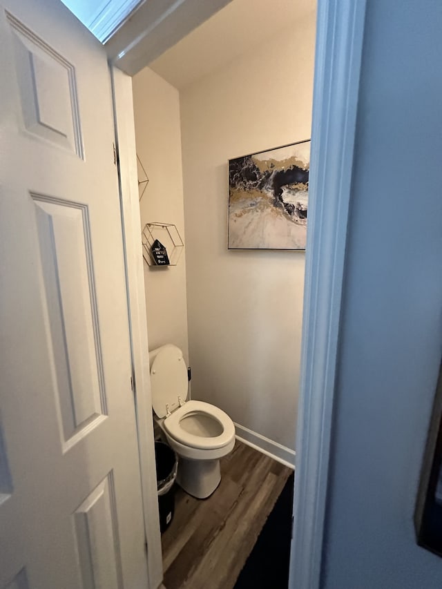 bathroom with toilet, a skylight, and hardwood / wood-style floors