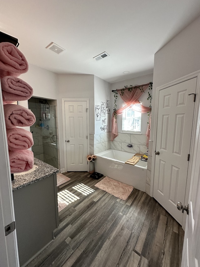 bathroom featuring wood-type flooring and plus walk in shower