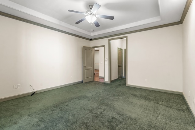 unfurnished bedroom with ornamental molding, a tray ceiling, dark carpet, and ceiling fan