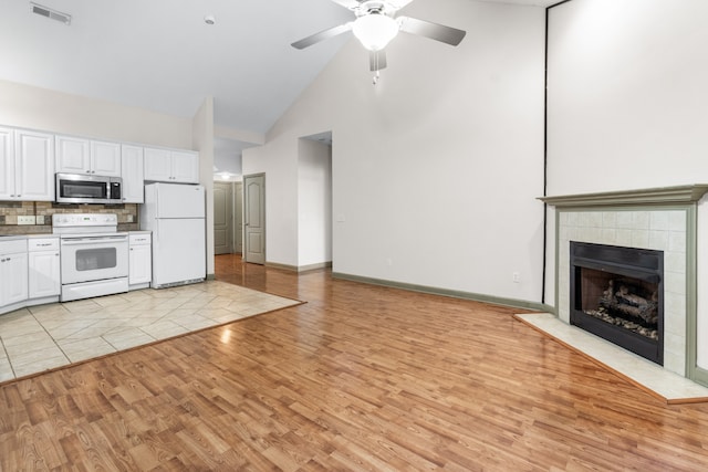 kitchen featuring white cabinets, high vaulted ceiling, light wood-type flooring, and white appliances