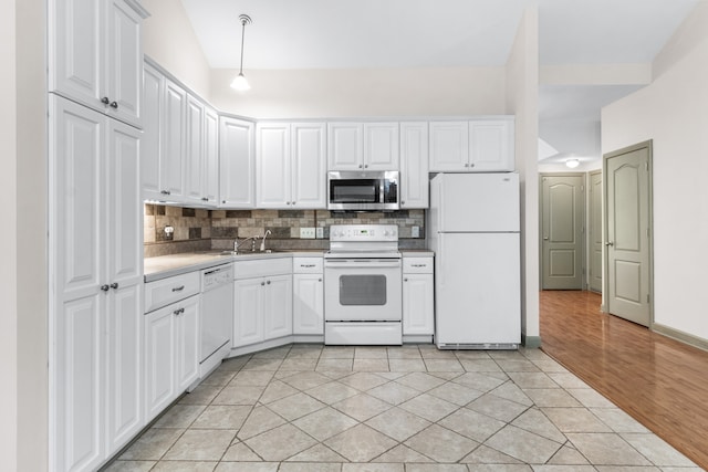 kitchen with white appliances, tasteful backsplash, light wood-type flooring, and white cabinets