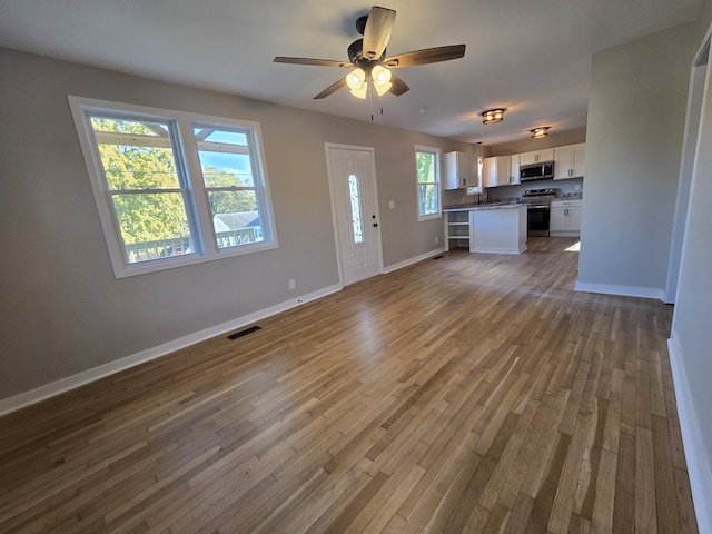 unfurnished living room featuring sink, dark hardwood / wood-style floors, and ceiling fan