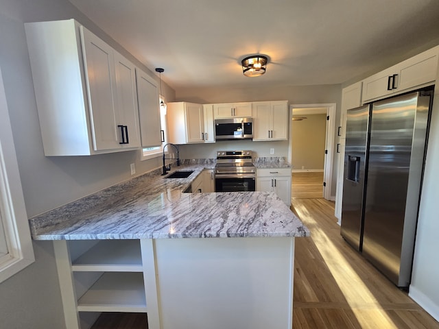 kitchen with appliances with stainless steel finishes, sink, white cabinets, and kitchen peninsula