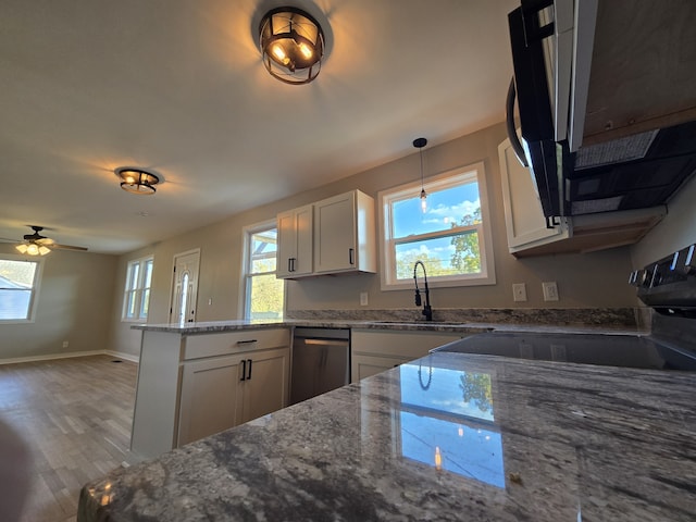 kitchen with sink, light stone counters, light wood-type flooring, kitchen peninsula, and white cabinets