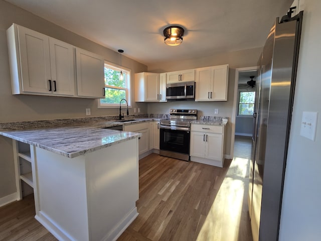 kitchen featuring pendant lighting, white cabinetry, light stone counters, kitchen peninsula, and stainless steel appliances