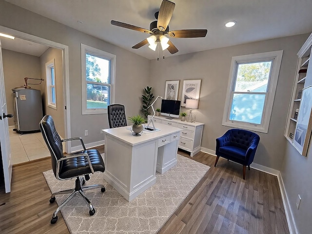 office featuring water heater, a healthy amount of sunlight, ceiling fan, and light hardwood / wood-style flooring